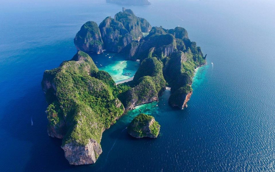 Longtail boats in a bay surrounded by limestone cliffs on Phi Phi Islands
