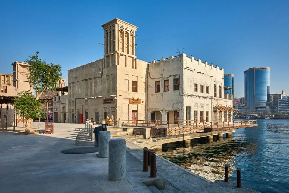 Traditional buildings and a modern yacht on Dubai Creek in Al Seef