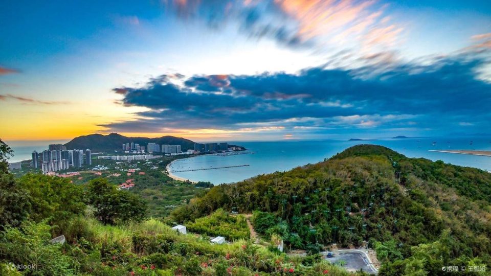 A panoramic sunset view from Luhuitou Park, showing Sanya Bay at dusk.