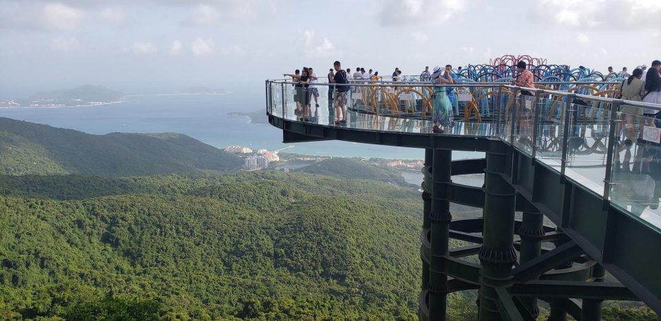 People walking on the suspension bridge in Yalong Bay Tropical Paradise Forest Park with lush forest views.