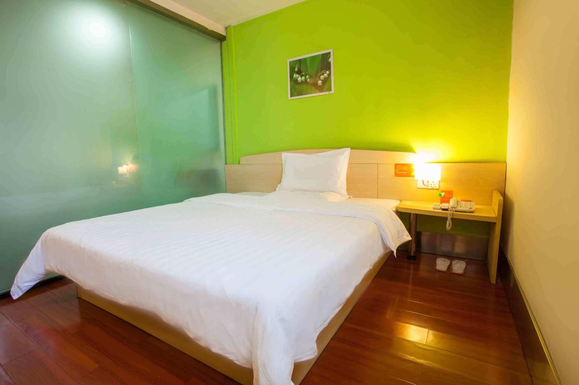 A simple, clean hotel room with a single bed and basic furnishings.