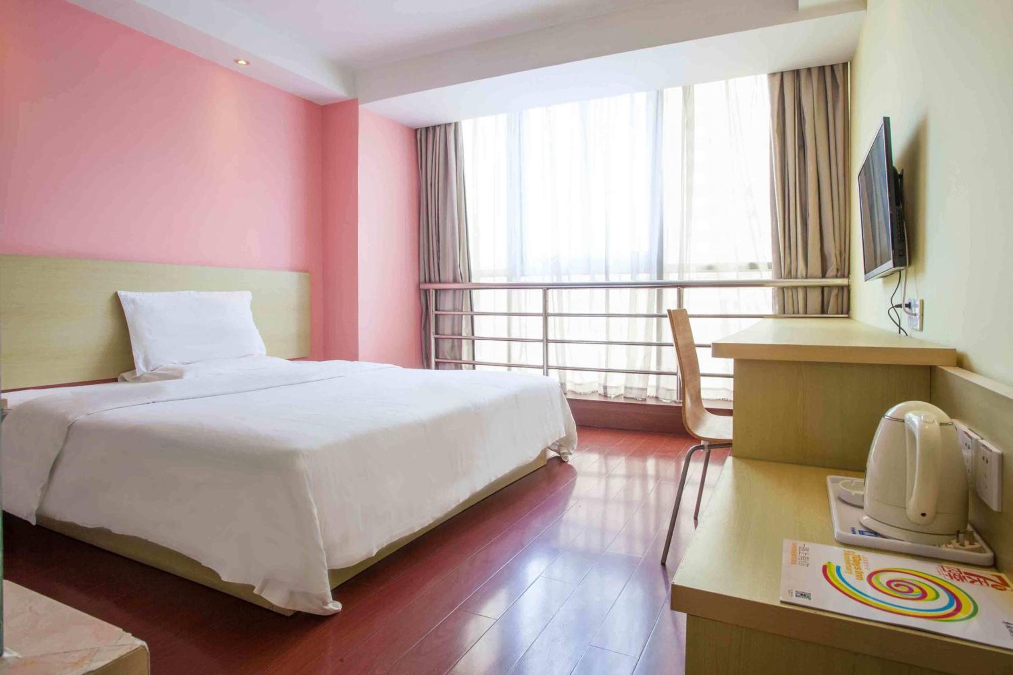 A basic hotel room with a double bed, a small desk, and a television.