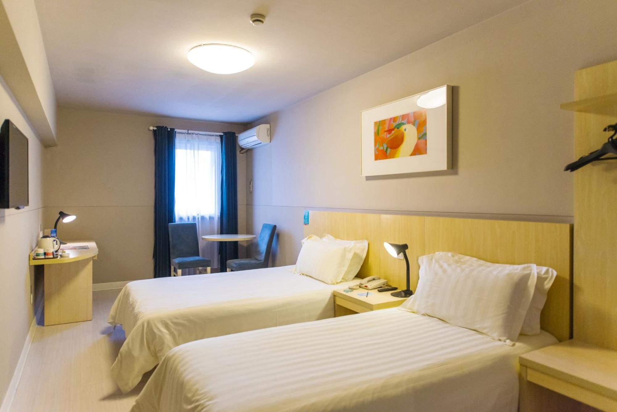 A clean, well-lit hotel room with a comfortable bed and a small workspace.
