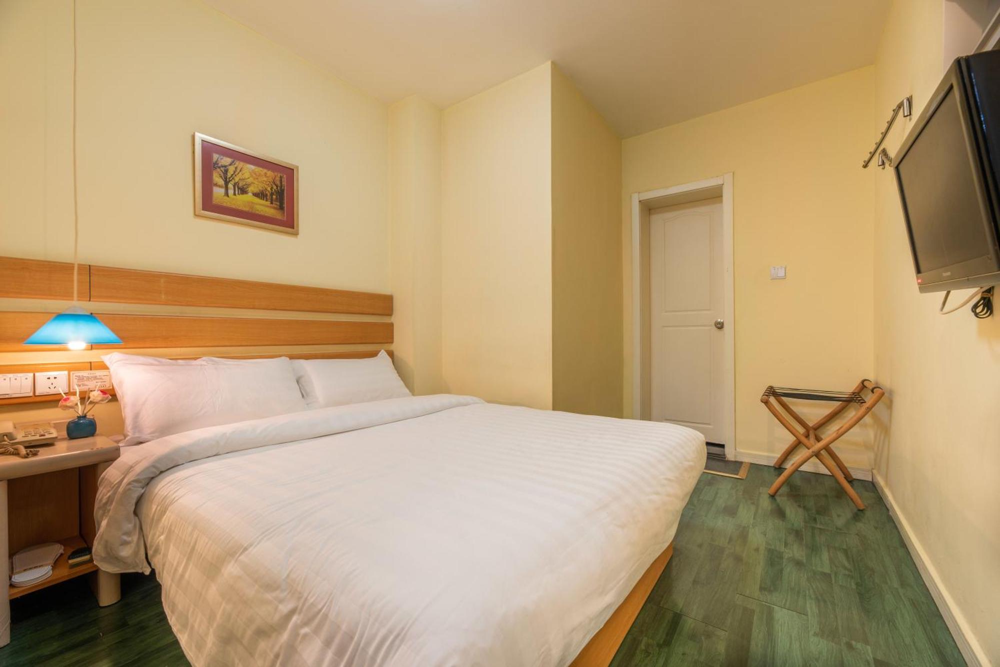 A basic hotel room featuring a single bed and a window.